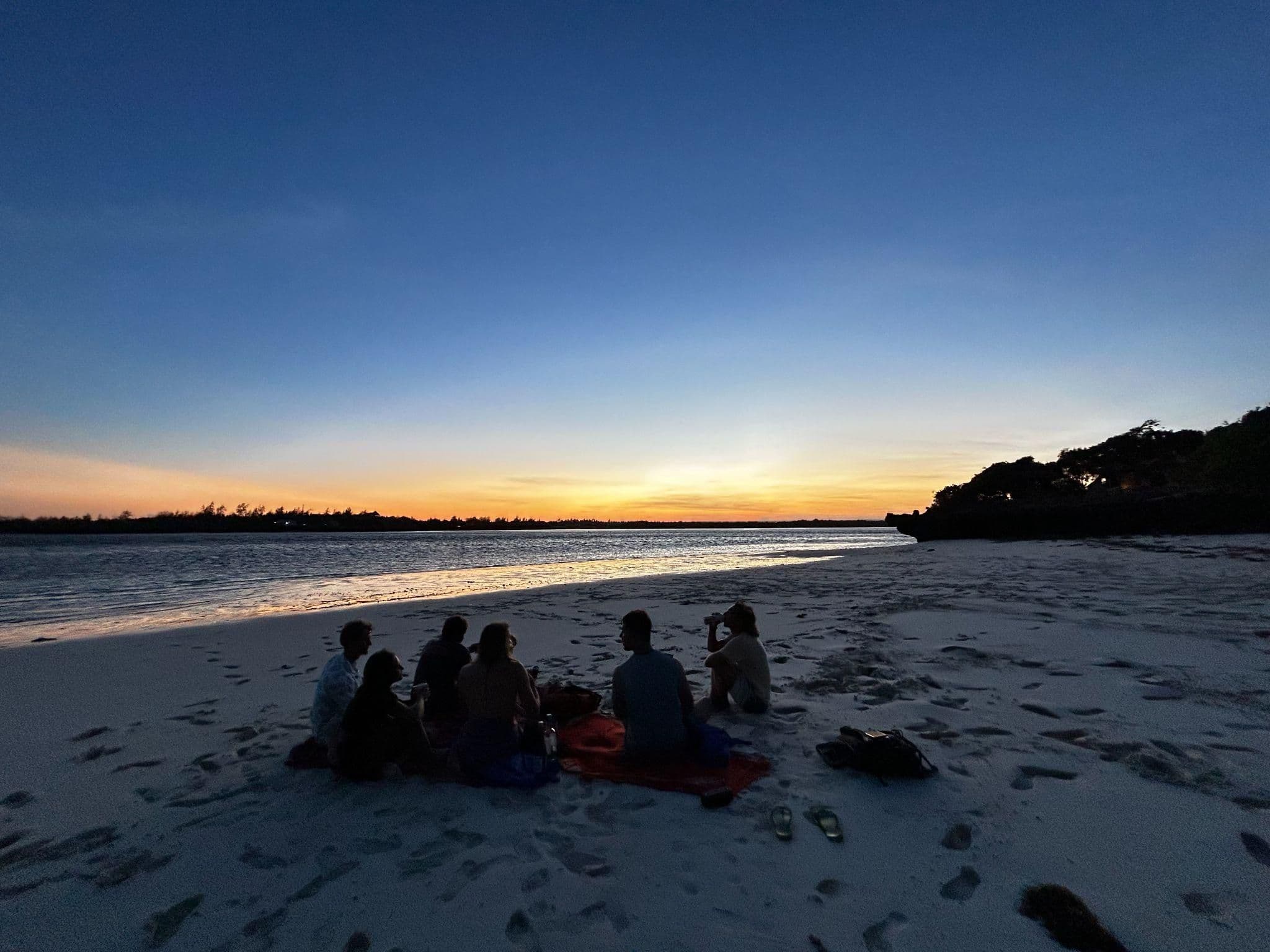 Friends watching the sunset over the water at Short Beach, Watamu, at the mouth of Mida Creek