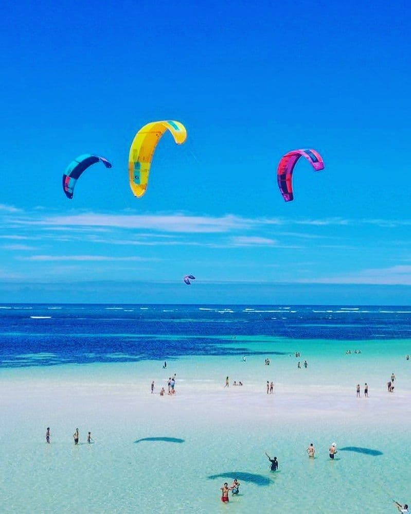 Colourful kitesurfing kites over the turquoise shallows and sandbank at Garoda Beach, Watamu